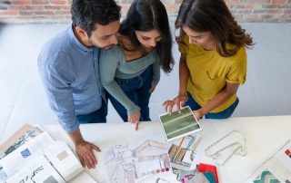 overhead photo of people looking at design samples and kitchen blueprints