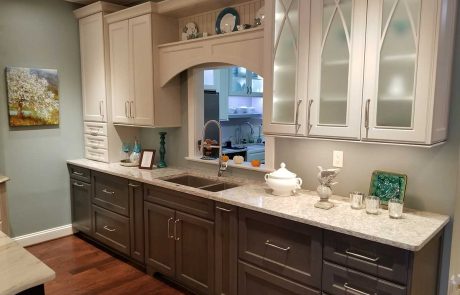 white cabinets with glass fronts above a sink and dark cabinets