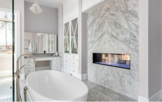 Modern bathroom with grey marble walls and a white soaking tub.