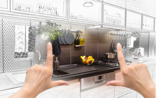 a person's hands held up in a frame shape over a drawing of a remodeled kitchen, envisioning the completed project int he middle of the drawing