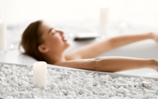 a woman leans back and relaxes in a soaking tub filled with bubbles