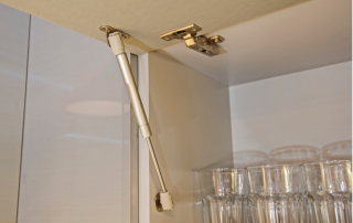 close-up photo of a cabinet door that opens upwards, showing modern hinges